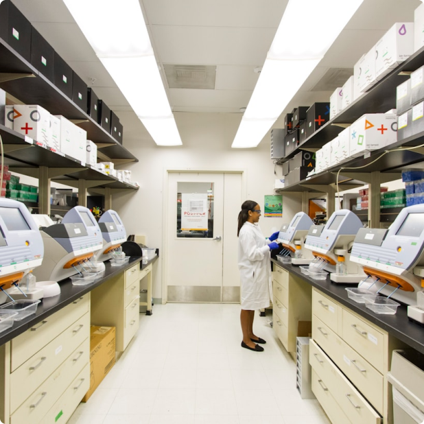 Scientist in a lab coat operating laboratory equipment in a bright research lab.